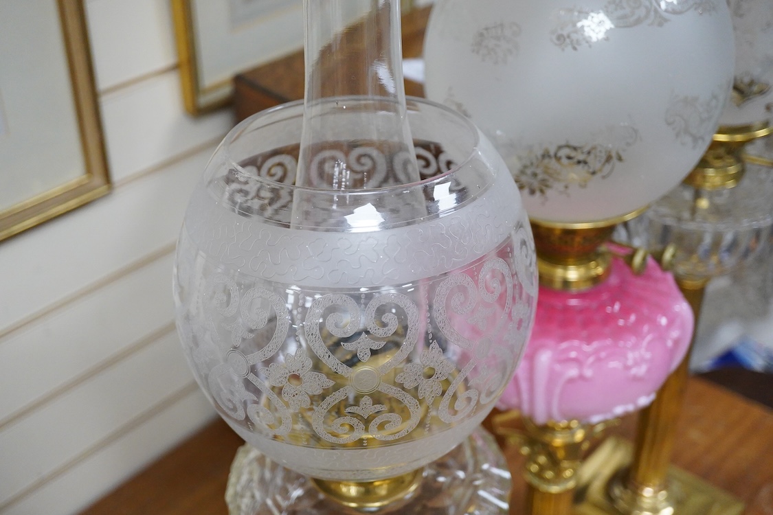 Three Victorian brass column oil lamps, with original brass fittings, glass reservoirs and shades. Tallest 72cm high.